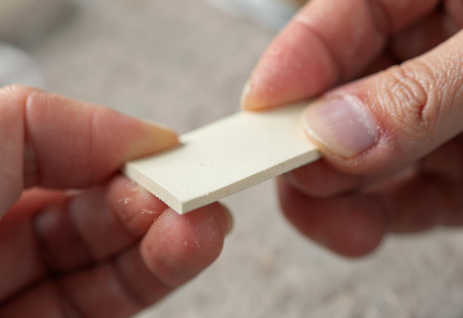 The edge of a ceramic tile held between two fingers